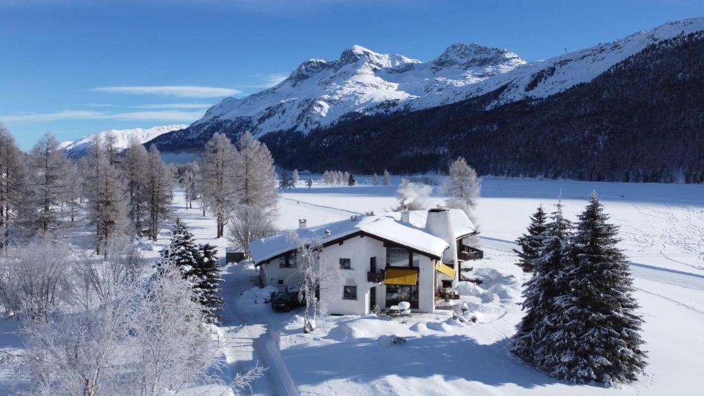 ein Haus im Schnee mit Bergen im Hintergrund in der Unterkunft Chesa Suot Ovas in Sils Maria