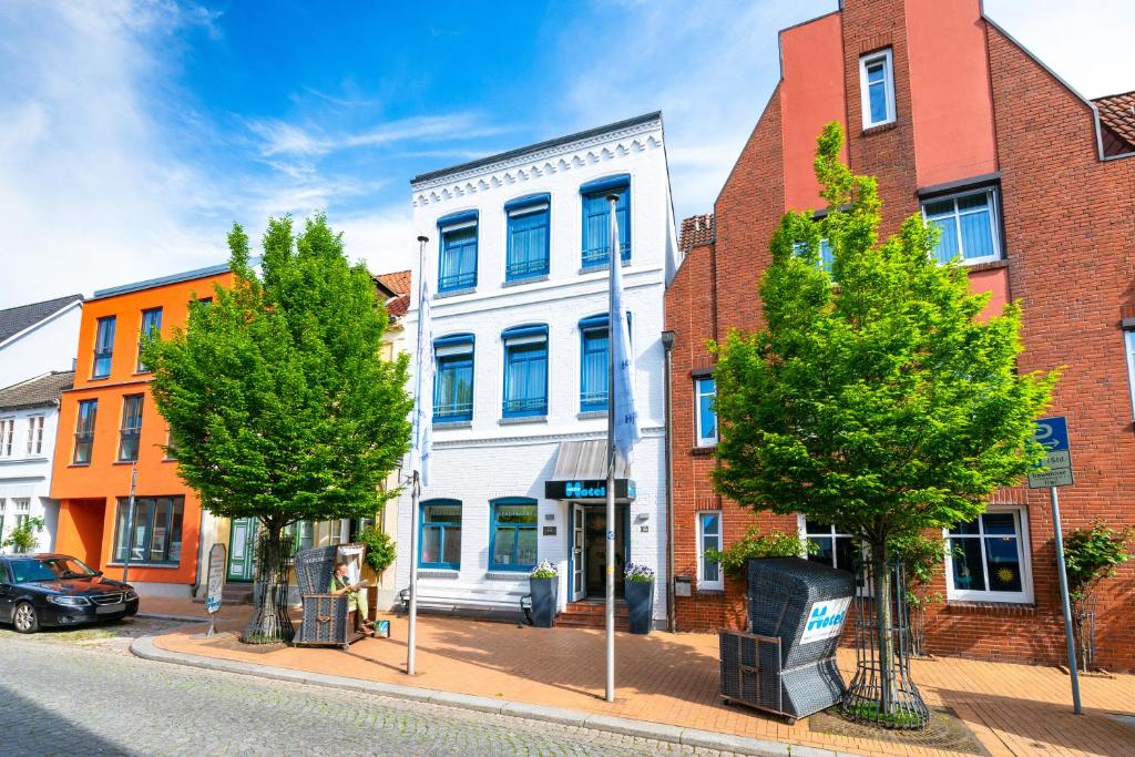 um edifício numa rua com árvores e edifícios em Nordsee-Hotel Hinrichsen em Husum