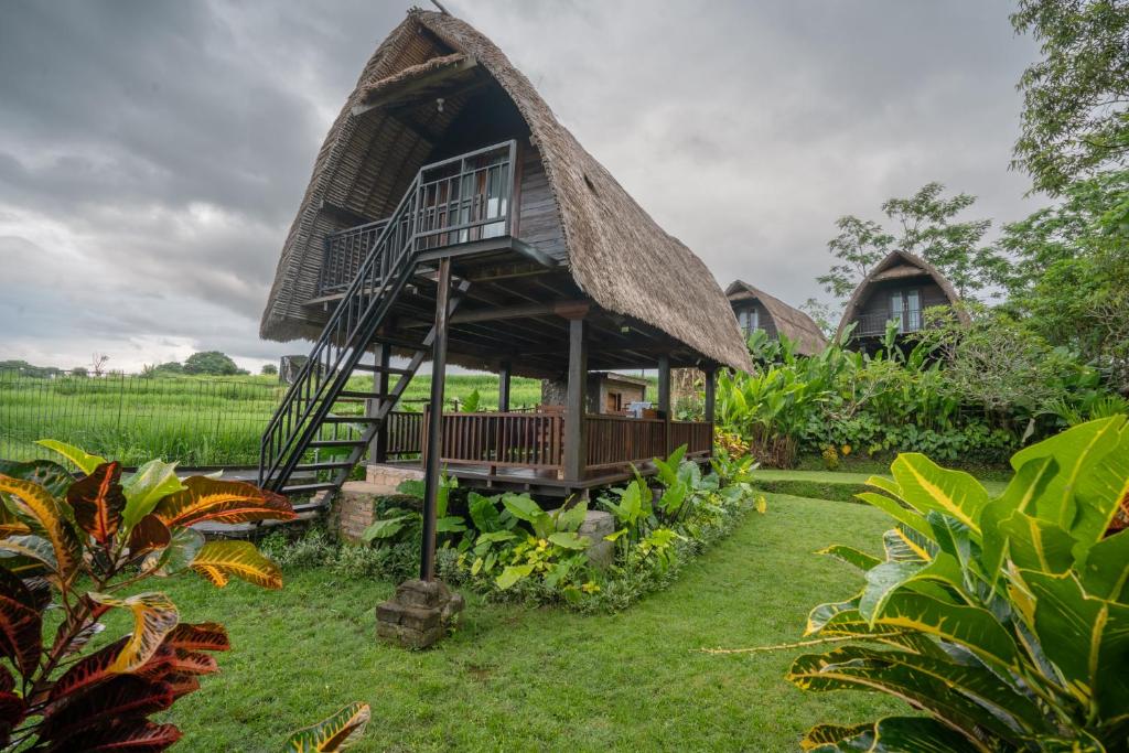 a house with a thatched roof and a yard at The Tetamian Bali in Sukawati