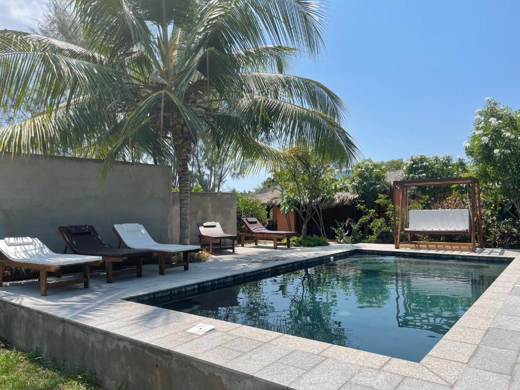 - une piscine avec des chaises et un palmier dans l'établissement maison vanilianadia, à Nosy Be