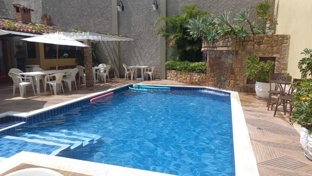 een zwembad met stoelen, een tafel en een parasol bij Pousada Cambucá de Cabo Frio in Cabo Frio