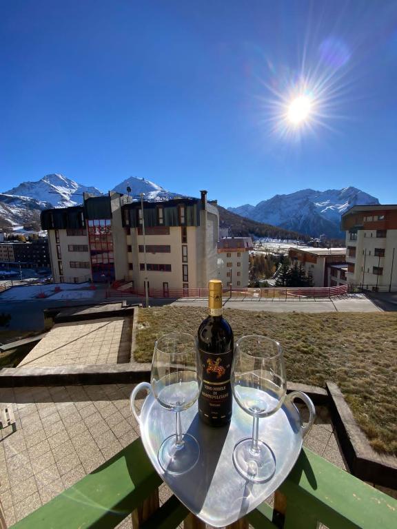 a bottle of wine sitting on a table with two wine glasses at Skyline su Sestriere in Sestriere