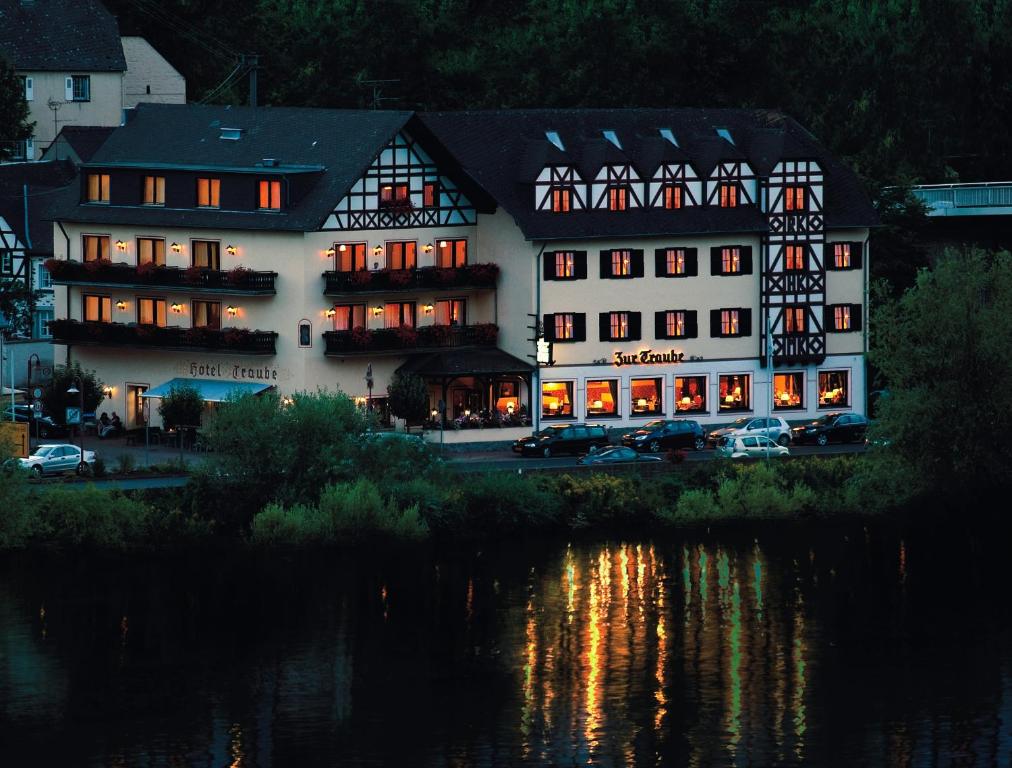 un grande edificio bianco accanto a un corpo d'acqua di Moselhotel & Restaurant Zur Traube GmbH a Löf