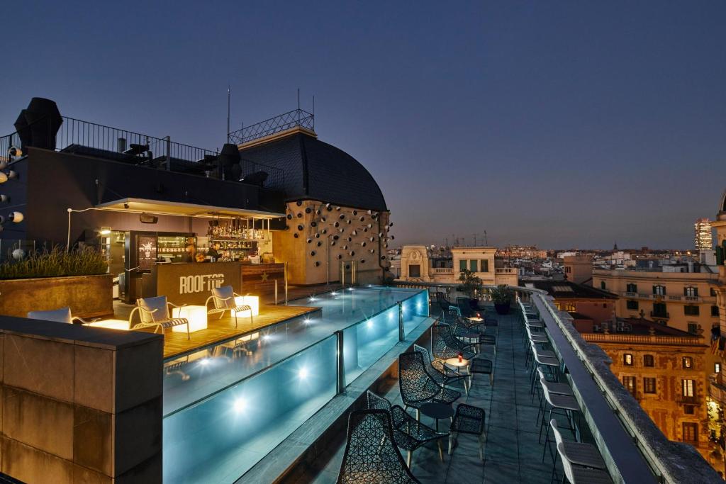 un bar sur le toit avec des chaises et des tables dans un bâtiment dans l'établissement Ohla Barcelona, à Barcelone