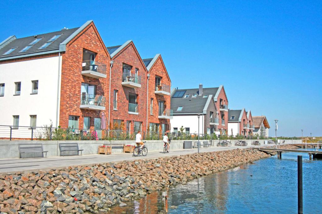 Ein Mann, der auf einem Bürgersteig neben Häusern Fahrrad fährt. in der Unterkunft Yachthafenblick in Heiligenhafen