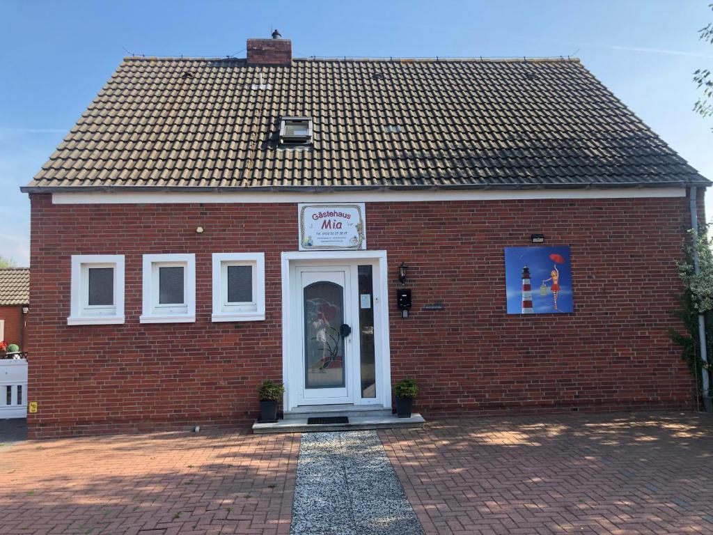 - un bâtiment en briques rouges avec une porte blanche dans l'établissement Gästehaus Mia, à Norddeich