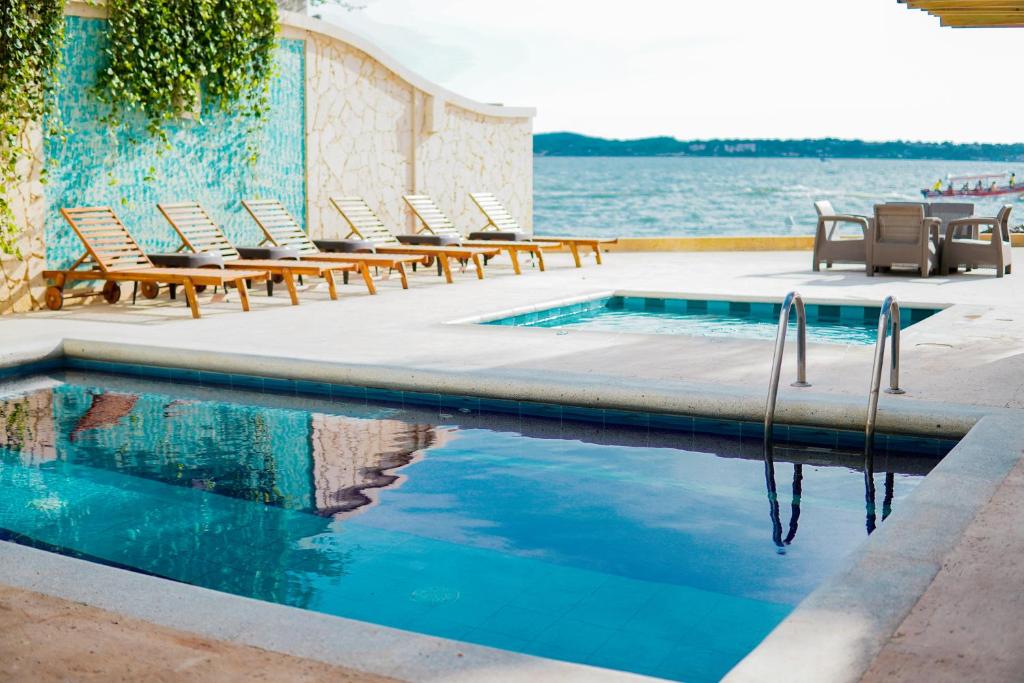 a swimming pool with lounge chairs next to the water at Hotel Caribbean Cartagena in Cartagena de Indias