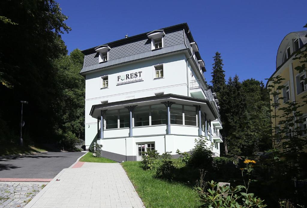 un edificio blanco con un cartel en el costado en Parkhotel Forest, en Mariánské Lázně