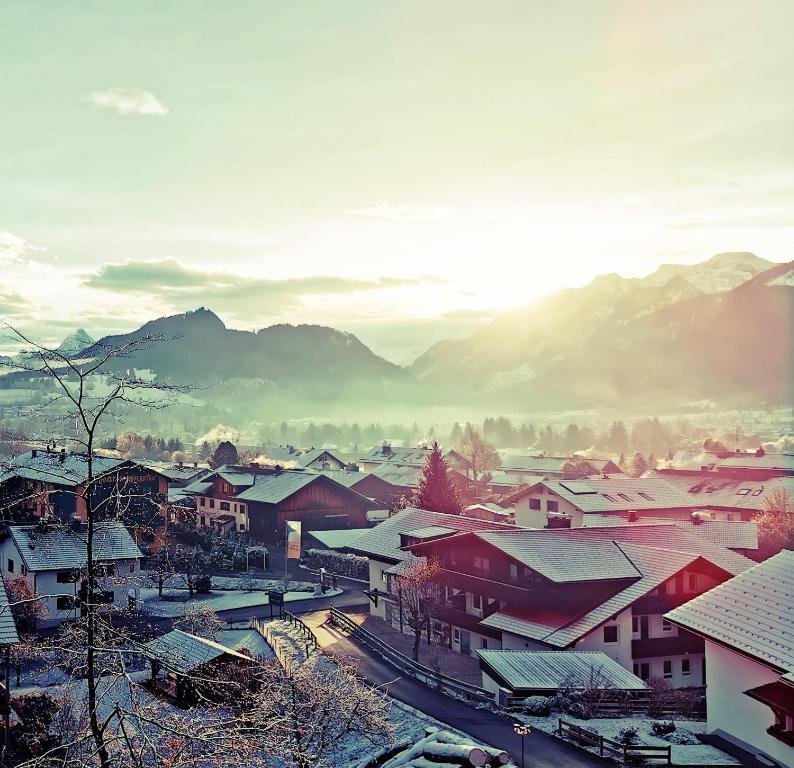 eine kleine Stadt mit schneebedeckten Dächern und Bergen in der Unterkunft Sunrise Belvedere Pfronten in Pfronten