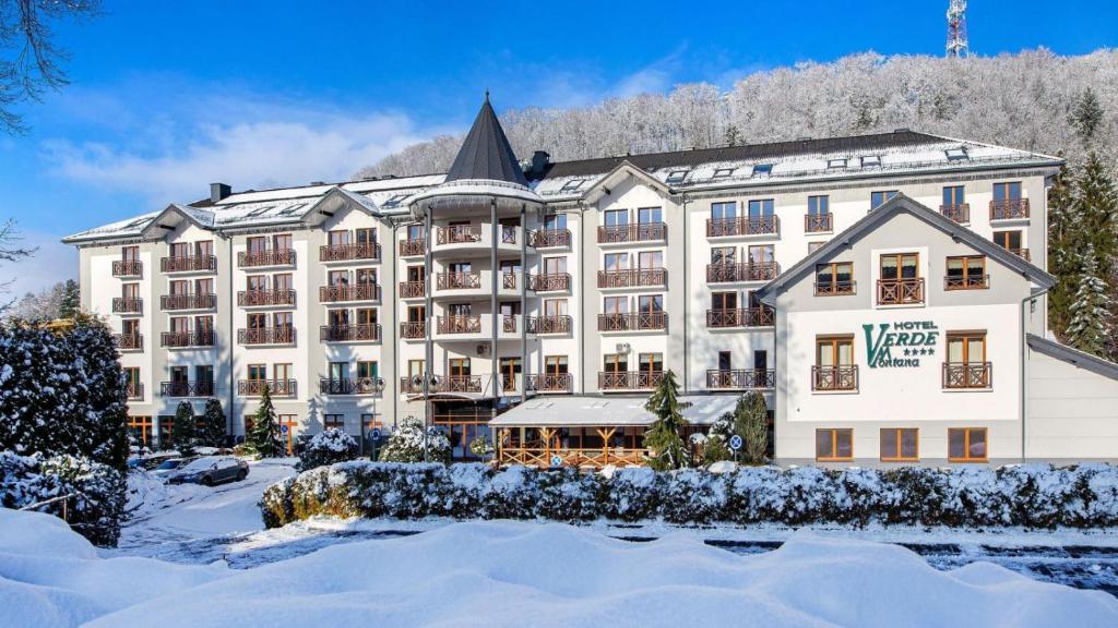 un grand hôtel avec de la neige devant lui dans l'établissement Hotel Verde Montana Wellness & Spa, à Kudowa-Zdrój