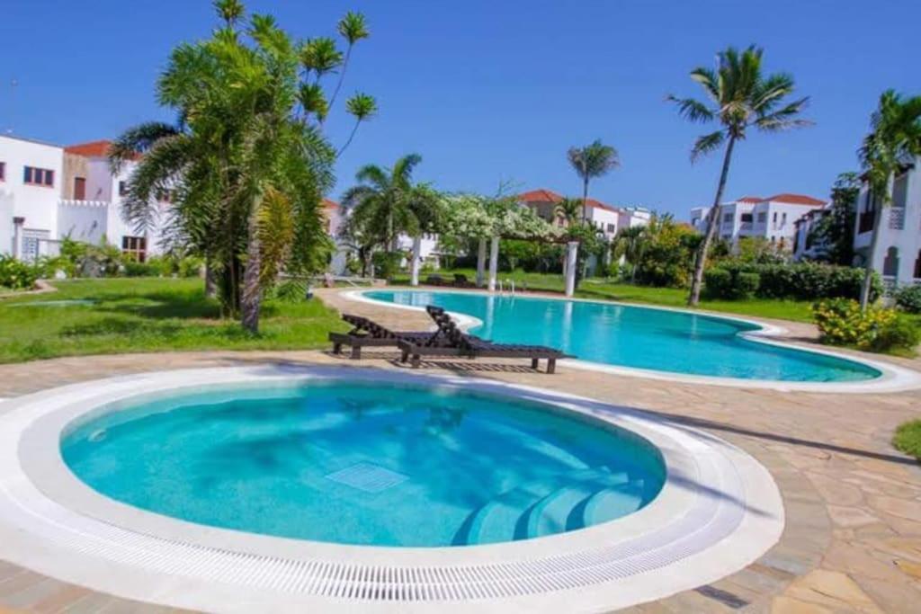 una grande piscina con due panchine in un cortile di The hayce residence a Kilifi