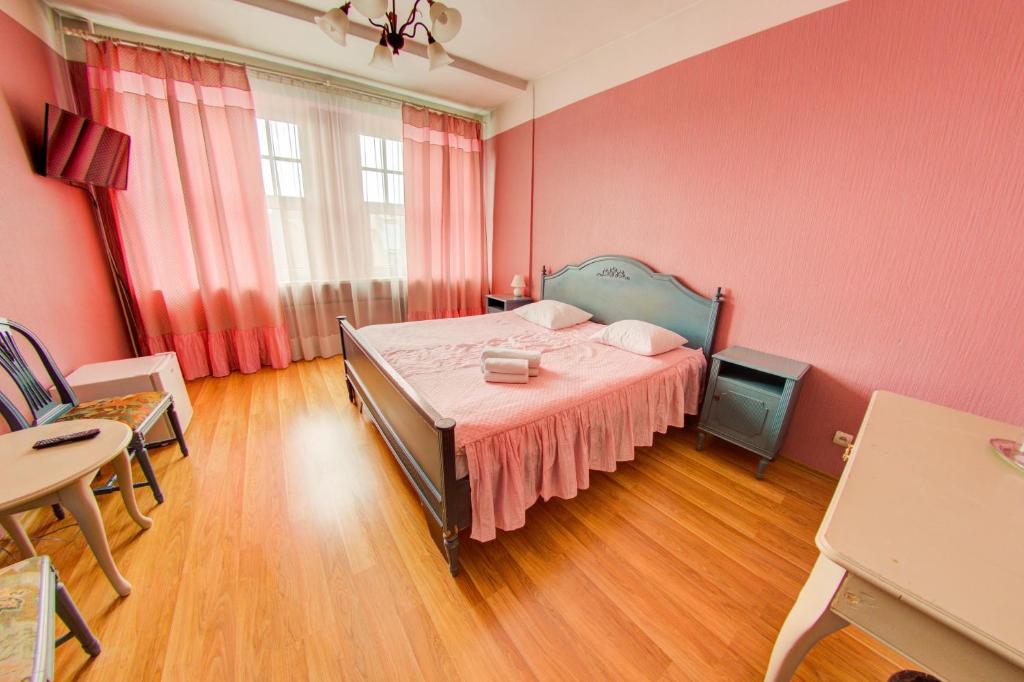 una camera da letto con un letto, pareti rosa e pavimenti in legno di Viktorija a Riga