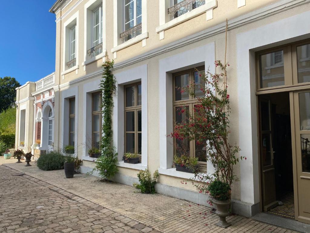 un bâtiment blanc avec des fenêtres et des plantes. dans l'établissement Au Jardin des Deux Ponts, à Abbeville