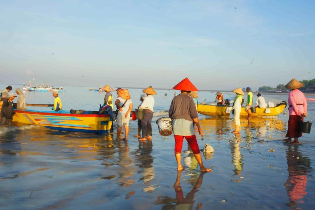 un grupo de personas de pie en una playa con barcos en Mango Tree Villas Jimbaran Bali, en Jimbaran