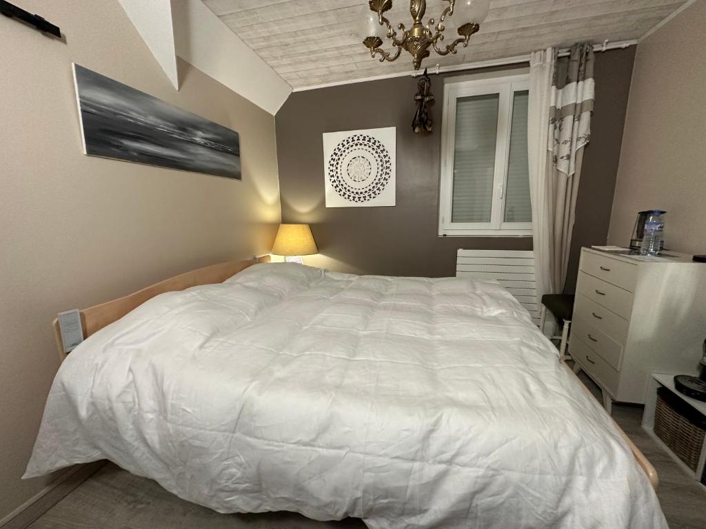 um quarto com uma grande cama branca e um lustre em Villa les Buissonets em Berck-sur-Mer