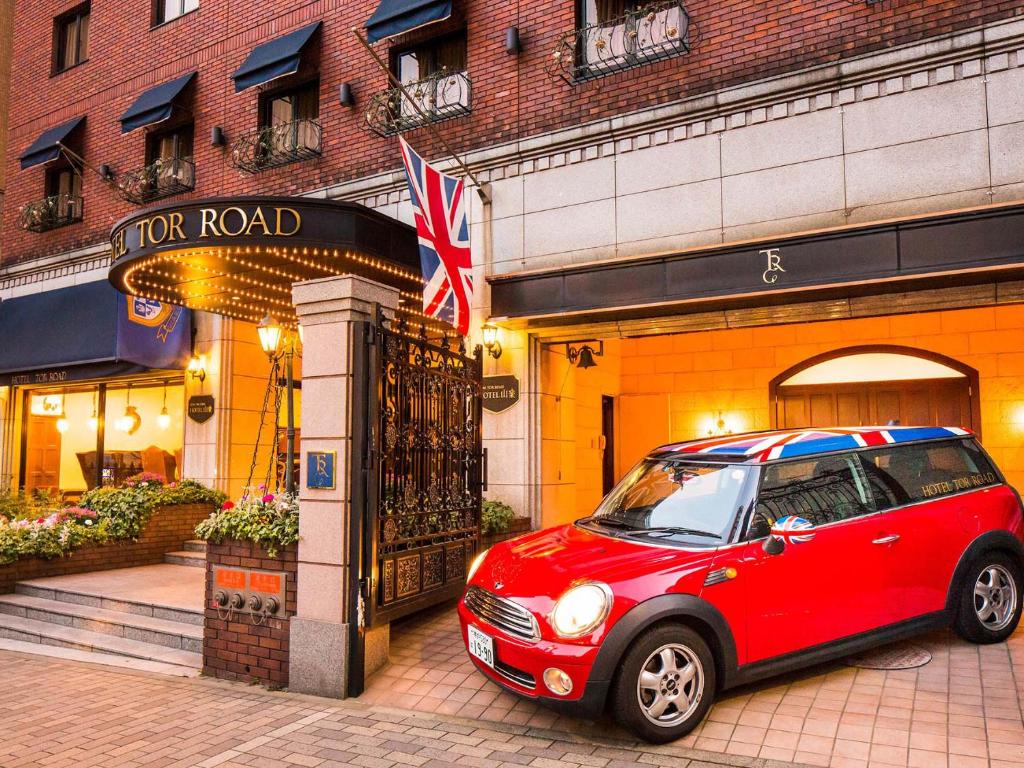 ein kleines rotes Auto, das vor einem Gebäude geparkt ist in der Unterkunft Kobe Tor Road Hotel Sanraku in Kōbe