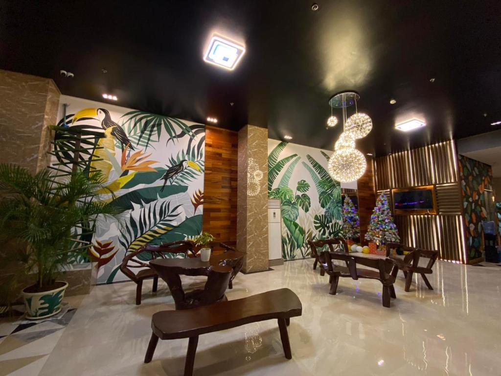 a lobby with tables and benches and a mural at NGN Gran Hotel in Tuguegarao City