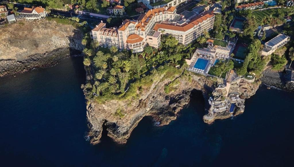 eine Luftansicht eines Hauses auf einer Insel im Wasser in der Unterkunft Reid's Palace, A Belmond Hotel, Madeira in Funchal