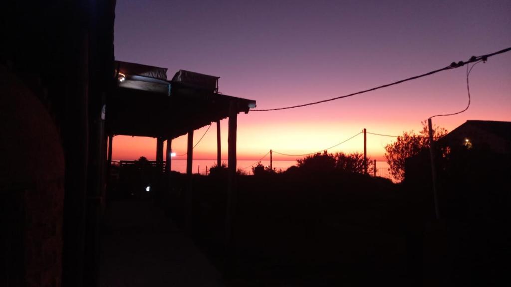 een zonsondergang in de lucht met een gebouw op de voorgrond bij Agua Corazones in San Luis