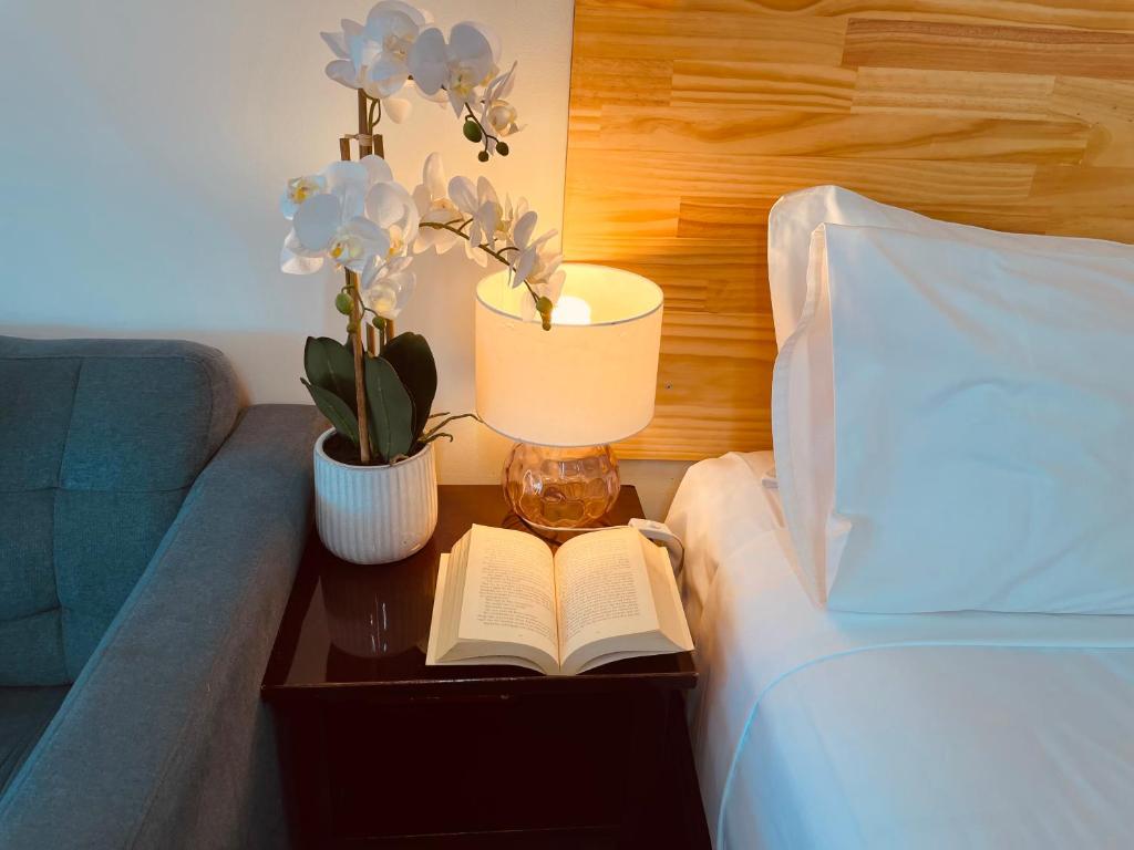 un lit avec une table, un livre et une lampe dans l'établissement Highway Motor Inn Taree, à Taree