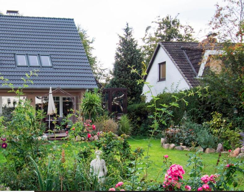 un jardín frente a una casa con flores en Dachgeschosswohnung Scharbeutz mit Garten, en Scharbeutz