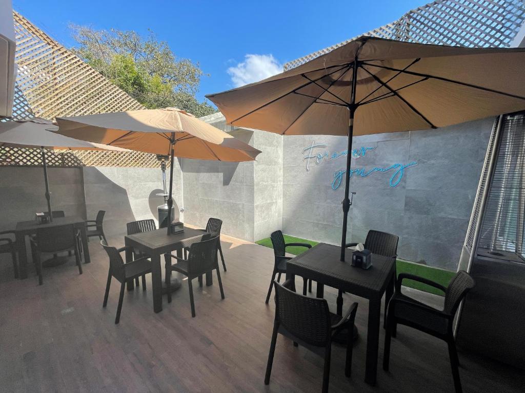 - deux tables et chaises avec parasols sur la terrasse dans l'établissement Hotel Villas Santander, à Guatemala