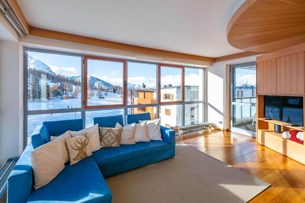 a living room with a blue couch and a large window at Terrazza su Sestriere Lux in Sestriere