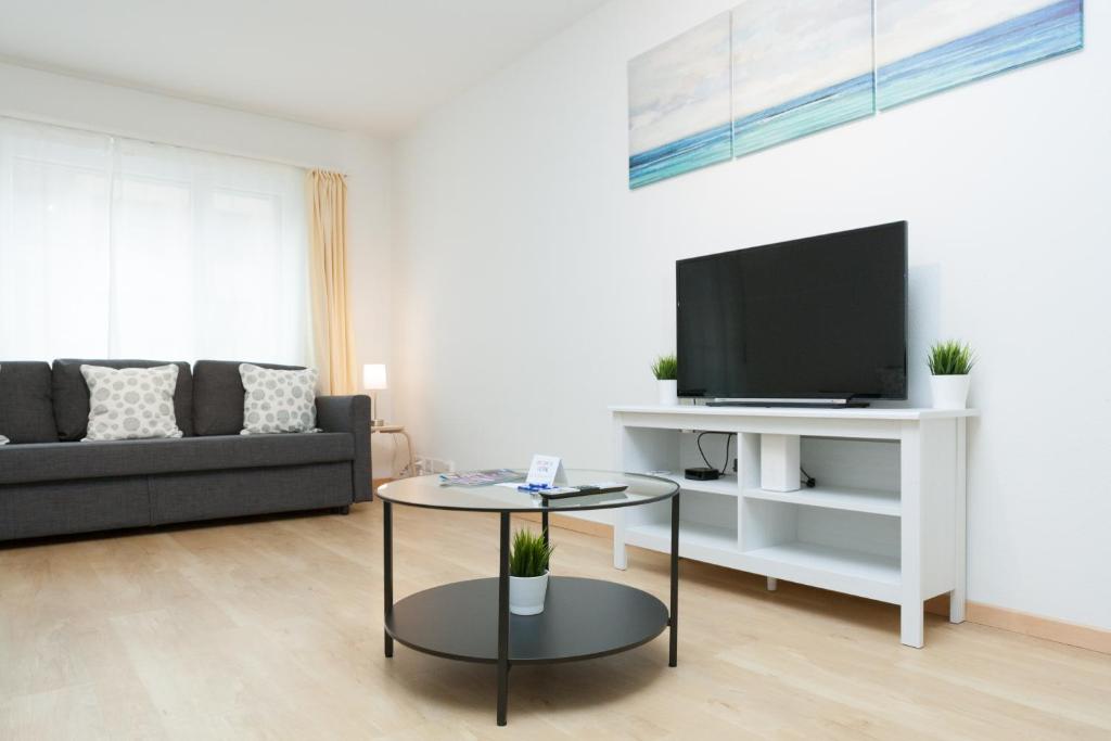 - un salon avec un canapé noir et une télévision dans l'établissement Galaxy Apartments Lucerne, à Lucerne