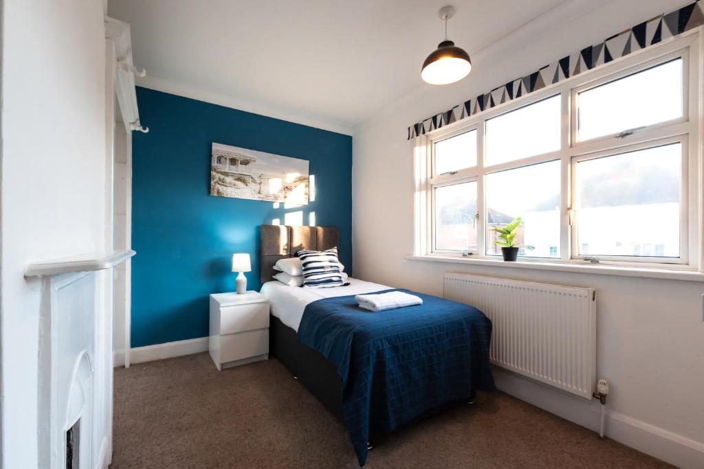 - une chambre avec un lit et un mur bleu dans l'établissement Comfortable and convenient stay 3 bed house, à Southampton