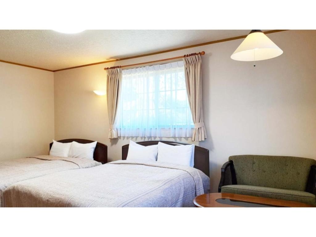 Cette chambre dispose de deux lits, d'une chaise et d'une fenêtre. dans l'établissement Sudomari no Yado Sunmore - Vacation STAY 46722v, à Nikkō