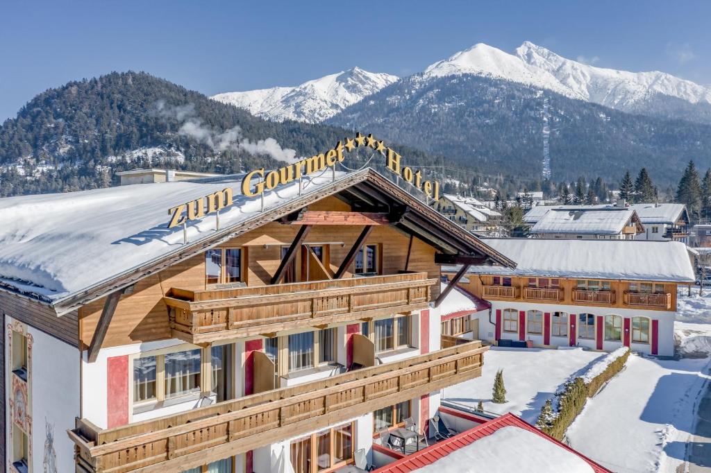 un bâtiment avec de la neige sur le toit et des montagnes en arrière-plan dans l'établissement Hotel Zum Gourmet, à Seefeld in Tirol