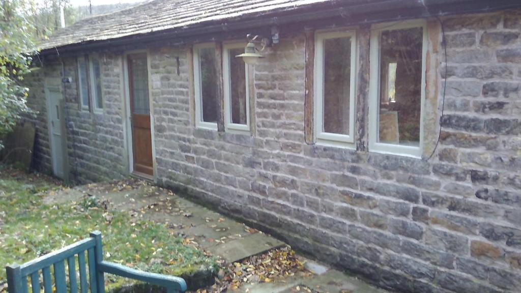 una casa di mattoni con una panchina davanti di Millstone cottage a Oldham