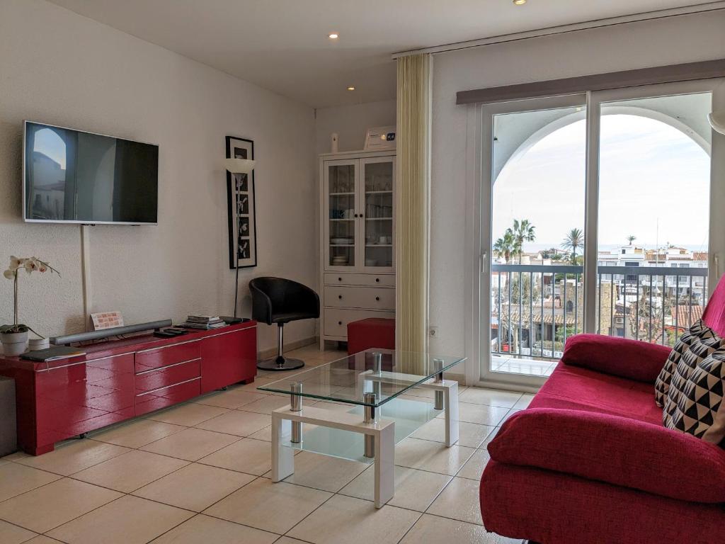 ein Wohnzimmer mit einem roten Sofa und einem TV in der Unterkunft Absolute Apartment in Empuriabrava