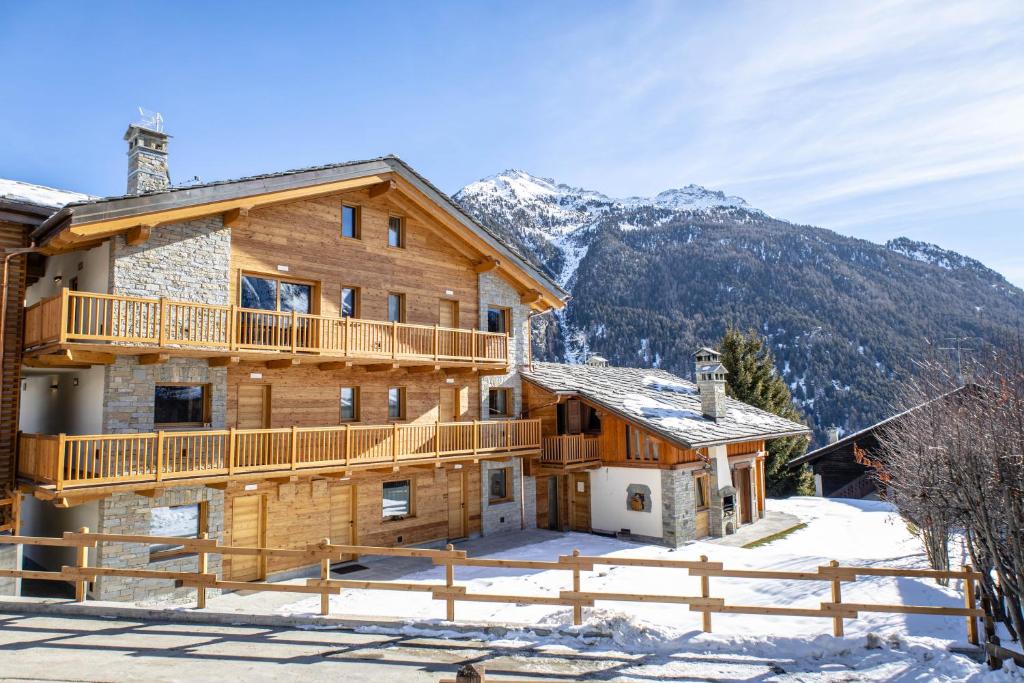 ein Blockhaus mit einer Terrasse im Schnee in der Unterkunft Fleur des neiges & Spa - Adults only in Ayas