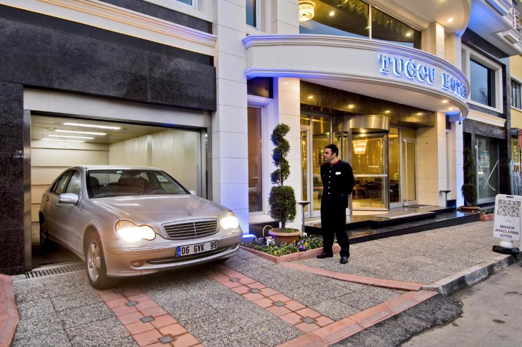 a man standing next to a car in front of a store at Tugcu Hotel Select in Bursa