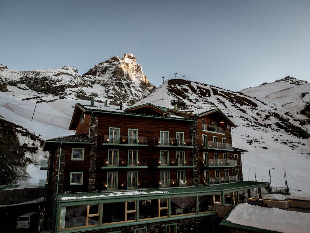 um edifício em frente a uma montanha coberta de neve em White Angel Hotel em Breuil-Cervinia