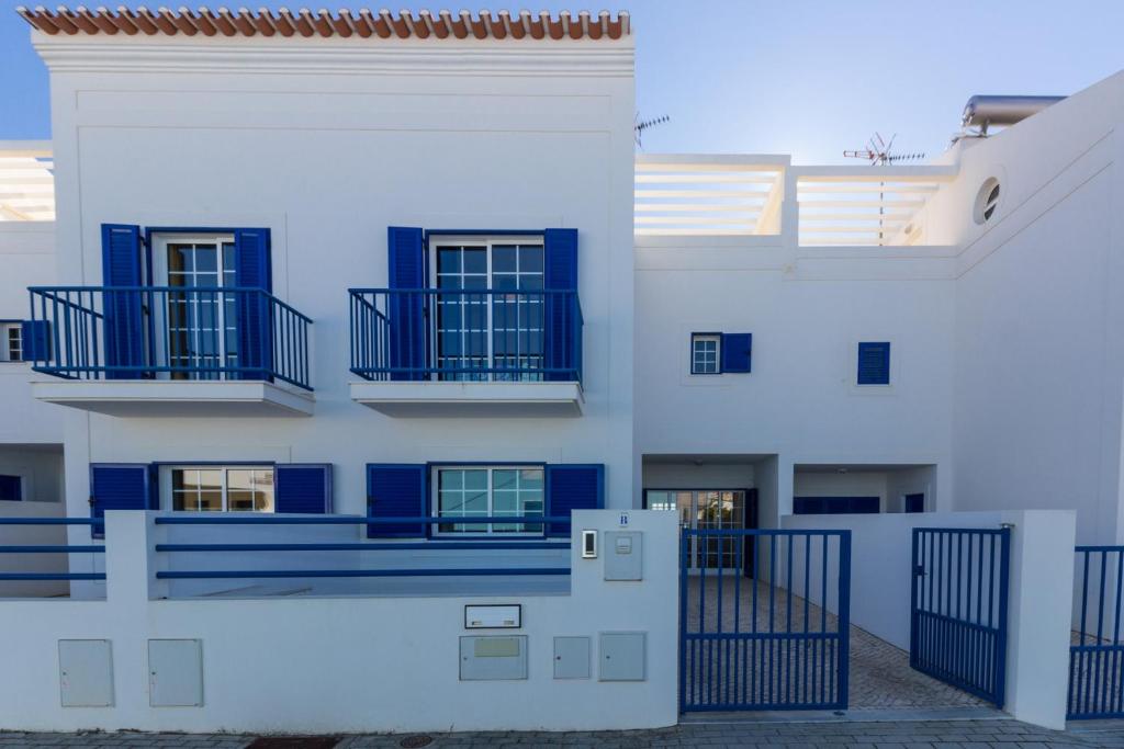 um edifício branco com varandas azuis e um portão em Blue Villa by ALGARVEMANTA na Manta Rota