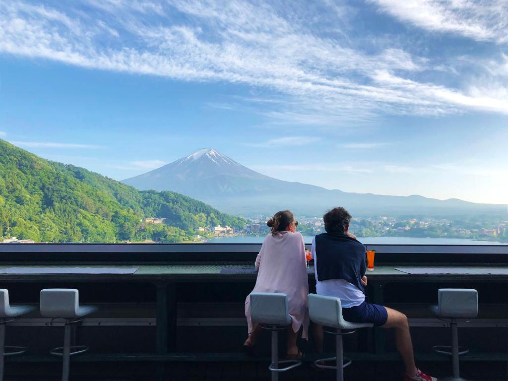 dos personas sentadas en sillas mirando a una montaña en Mizno Hotel en Fujikawaguchiko