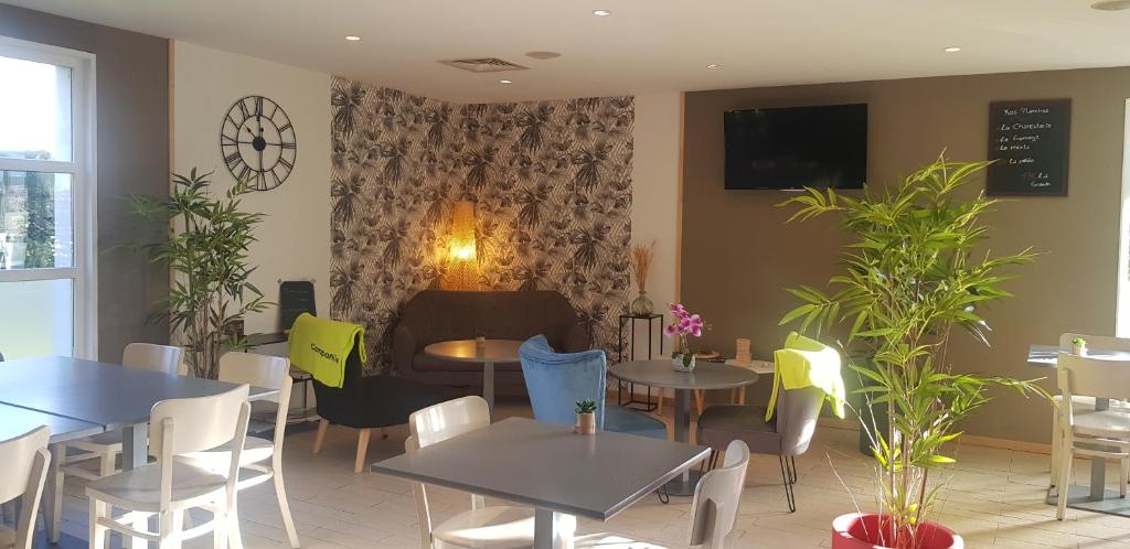 a restaurant with tables and chairs and a tv on the wall at Campanile Hotel Chantilly in Chantilly