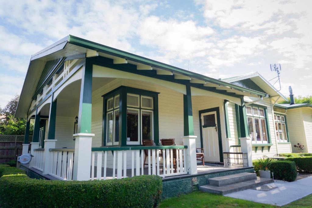 a small yellow and green house with a porch at Gumnut House. in Whanganui