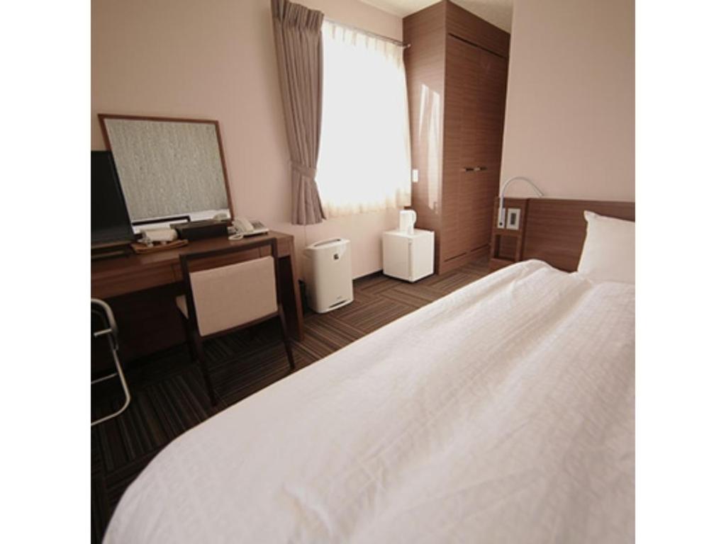 Business Hotel Goi Onsen - Vacation STAY 78233v في Ichihara: غرفة نوم بسرير ومكتب ومرآة