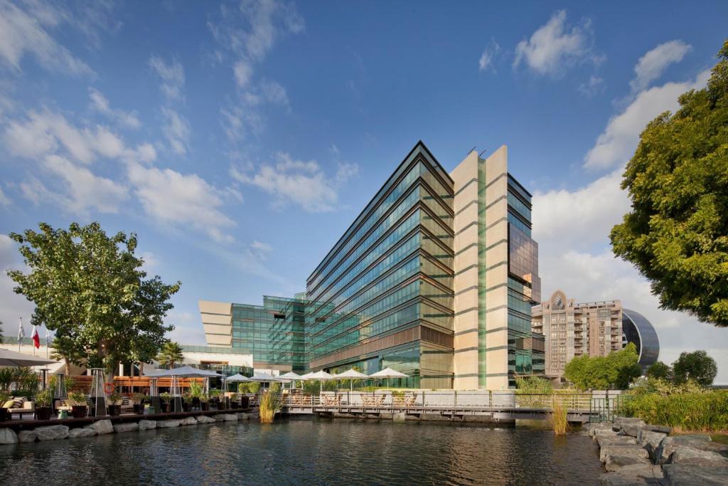 ein hohes Glasgebäude neben einem Fluss in der Unterkunft Jumeirah Creekside Dubai in Dubai