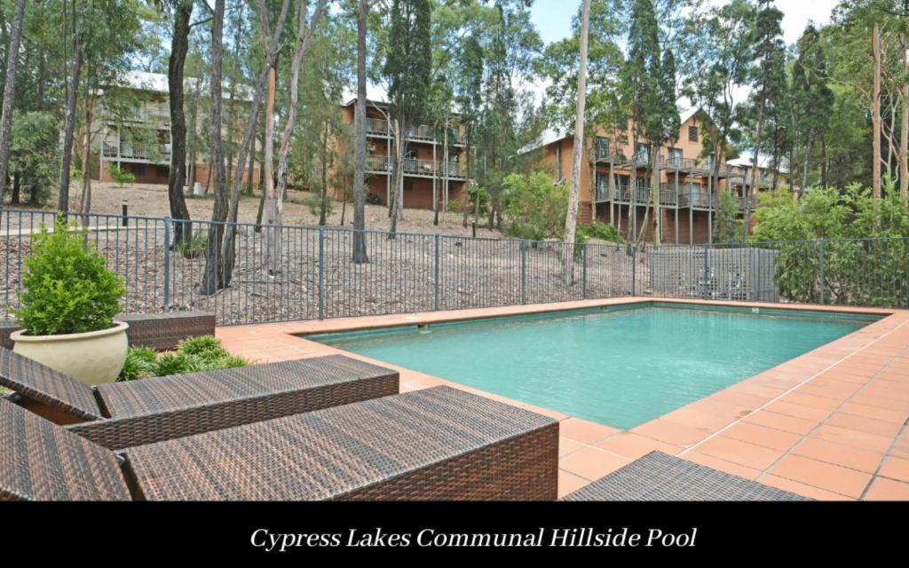 a swimming pool with two chairs and a fence at Villa 3br Chardonnay Villa located within Cypress Lakes Resort in Pokolbin