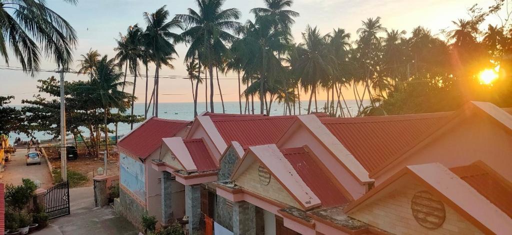 uma fileira de casas com palmeiras e o oceano em Lang Chai Guesthouse em Mui Ne