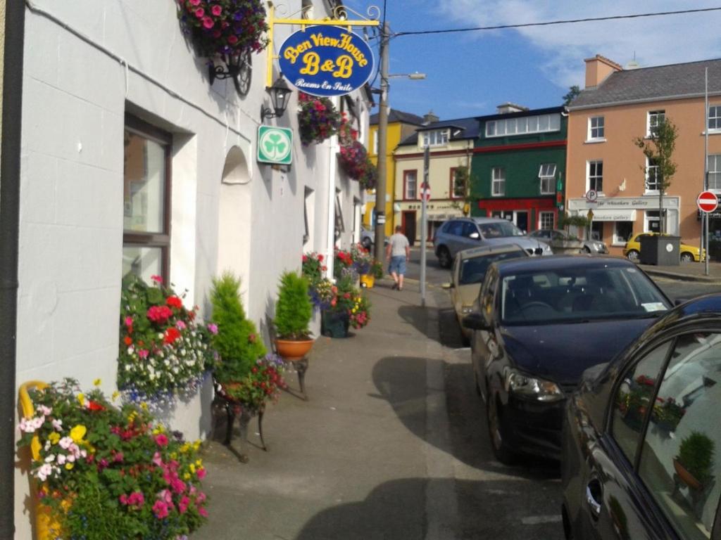 a street with parked cars and flowers on the sidewalk at Ben View Guesthouse in Clifden