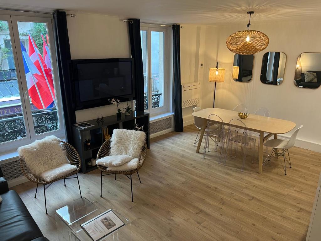 un soggiorno con tavolo, sedie e TV di NOTRE DAME - STYLISH APARTMENT a Parigi