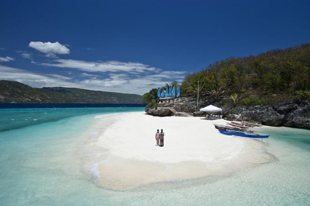 2 personnes debout sur une plage dans l'eau dans l'établissement Bluewater Sumilon Island Resort, à Sumilon Island