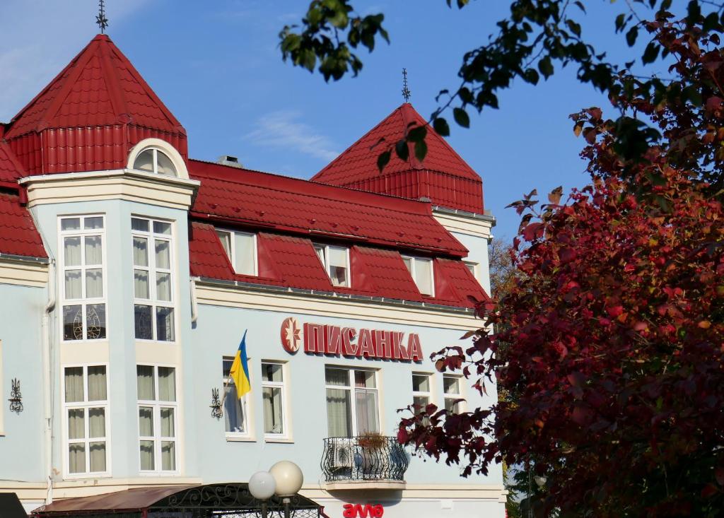 un grand bâtiment blanc avec un toit rouge dans l'établissement Pysanka Hotel, à Kolomya