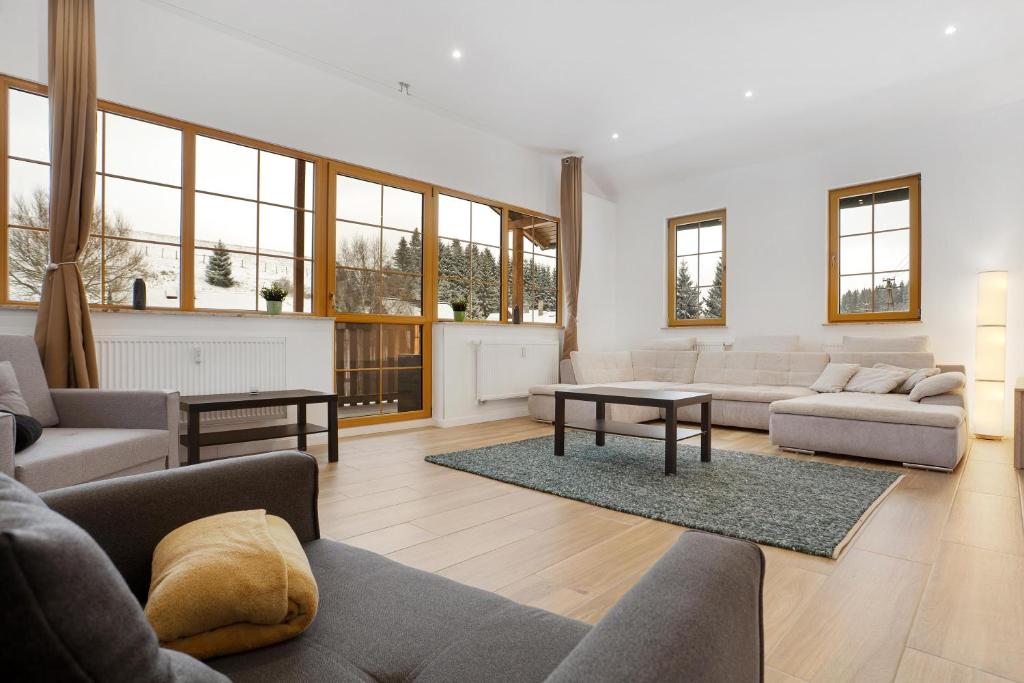 a living room with couches and tables and windows at Apartmán Ela in Horní Blatná