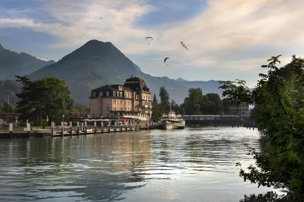 Ein Fluss mit einem Gebäude und Vögeln, die darüber fliegen. in der Unterkunft Hotel Du Lac in Interlaken